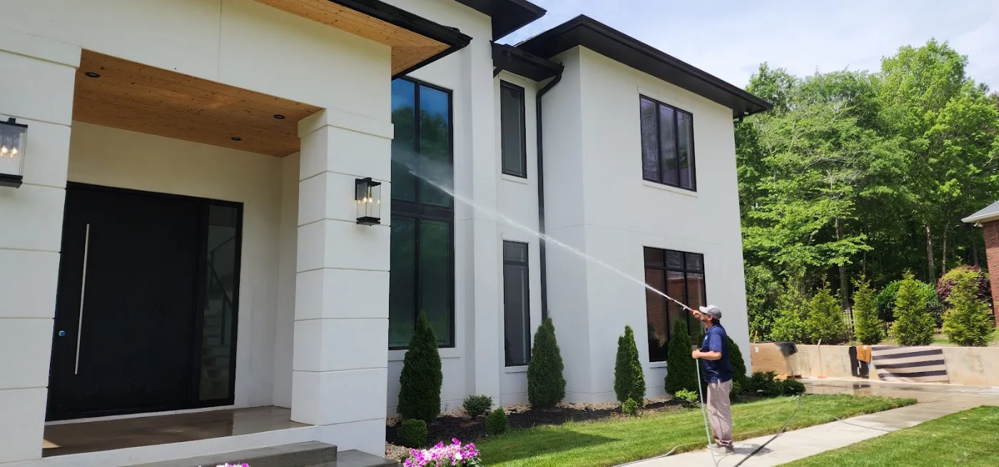 Power Clean technician soft washing the exterior of a modern home